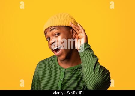 Lauschangriffe. Neugieriger schwarzer Kerl mit der Hand in der Nähe des Ohrs, der versucht, etwas zu hören Stockfoto