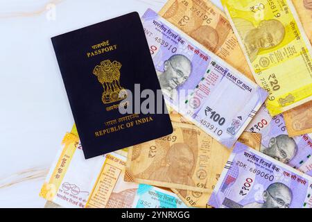 Indischer Pass ruht auf einer Sammlung von bunten indischen Rupien Geldscheine, die die Währung der Reise zeigen. Stockfoto