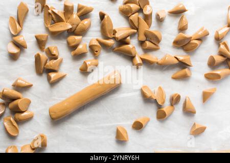 Blick von oben auf Iloka-Bonbons auf Pergamentpapier, gekochte Kondensmilch-Bonbons, nigerianische Iloka-Bonbons auf weißem Hintergrund, die Karamell-harte Bonbons herstellen Stockfoto