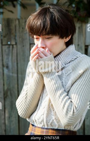 Eine Frau in den 20ern wärmt ihre beißenden Hände Stockfoto