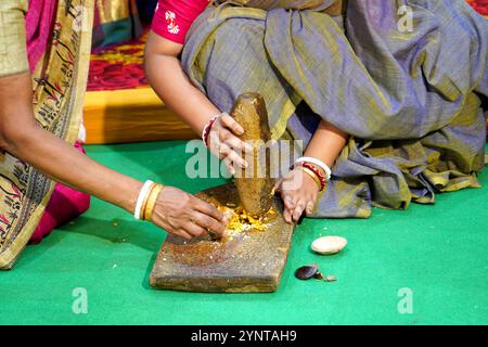 Bengalische Frau, die Kurkuma-Paste in Shil Nora für haldi-Funktion herstellt Stockfoto