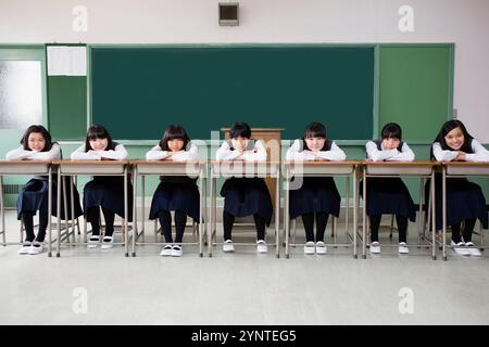 Mädchen, die auf einer Reihe von Schreibtischen sitzen Stockfoto