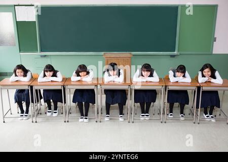 Mädchen, die auf einer Reihe von Schreibtischen sitzen Stockfoto