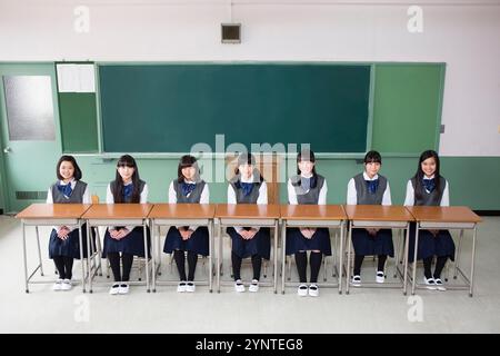 Mädchen, die auf einer Reihe von Schreibtischen sitzen Stockfoto