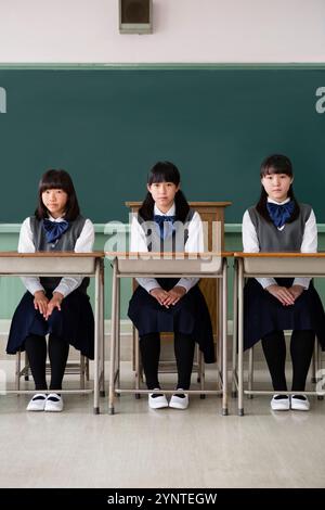 Mädchen, die auf einer Reihe von Schreibtischen sitzen Stockfoto
