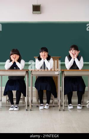 Mädchen, die auf einer Reihe von Schreibtischen sitzen Stockfoto