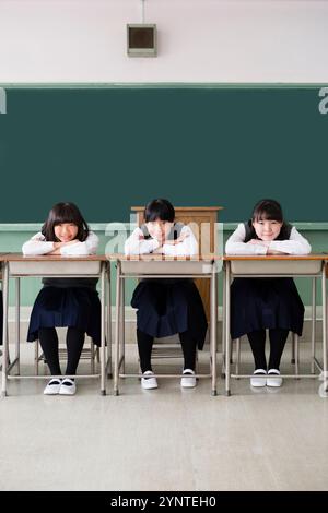 Mädchen, die auf einer Reihe von Schreibtischen sitzen Stockfoto