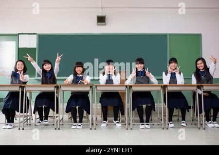 Schulmädchen sitzen in einer Reihe und friedlich Stockfoto