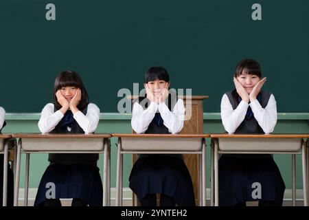 Mädchen, die auf einer Reihe von Schreibtischen sitzen Stockfoto