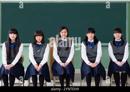 Studentin sitzt auf einem Stuhl in einer Reihe in einem Klassenzimmer Stockfoto