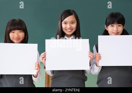 Studentinnen sitzen in einer Reihe und halten ein Brett in einem Klassenzimmer Stockfoto