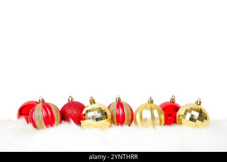 Rote und goldene Weihnachtskugeln Ornamente auf weißem Pelz auf weißem Hintergrund mit Kopierraum für Textdekoration Stockfoto