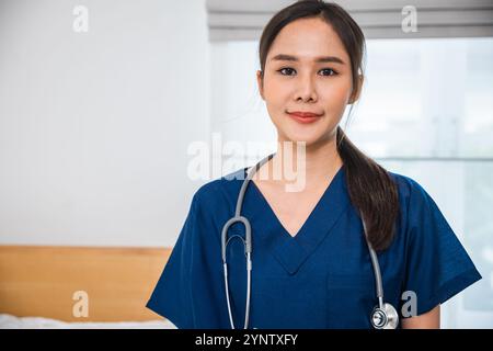 Asiatische weibliche Gesundheitsberaterin in den Peelings, die in einem Krankenhauszimmer stehen, Porträt der glücklichen Frau Stockfoto