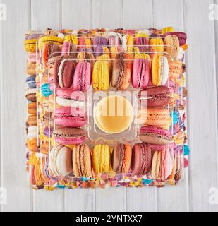Ein quadratisches Arrangement aus farbenfrohen Macarons, die von oben betrachtet werden und ihre zarte Textur und ihr elegantes Design hervorheben. Stockfoto