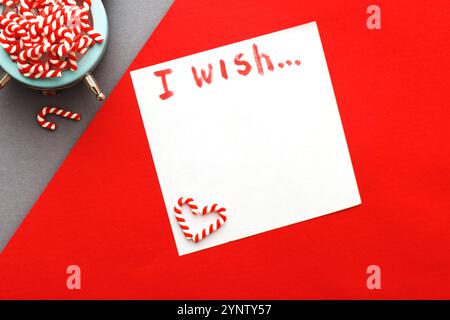 Weihnachtshintergrund mit Zuckerstöcken mit Wecker auf blaugrauem und rotem Hintergrund. Stockfoto