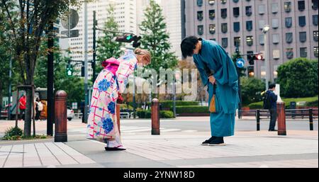 Respekt, japaner und Verbeugung für Begrüßung, Kultur und Willkommen mit Kimono in der Stadt. Traditionelle Mode, Mann und Frau mit Einführung in die Stadt Stockfoto