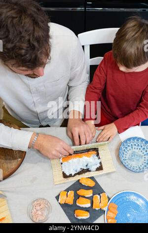 Kaukasischer Vater und Sohn bereiten zusammen Sushi zu Hause zu Stockfoto