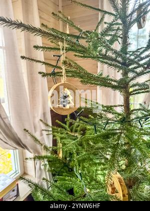 Rustikales hölzernes Weihnachtsschmuck hängt drinnen an grünem Baumzweig. Hochwertige Fotos Stockfoto