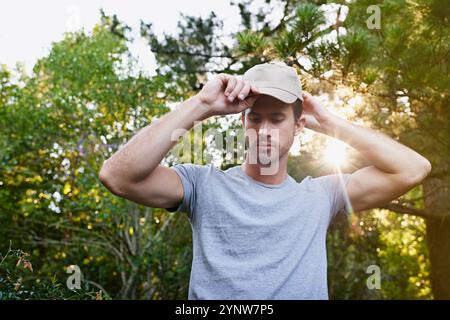 Cap, Wandern und Berge mit Mann im Wald für morgendliche Abenteuer, Reisen oder Trekking im Freien. Sport, Fitness und Training mit ernsthaftem Wanderer Stockfoto