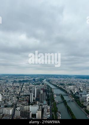 Ein atemberaubender Blick aus der Luft auf Paris mit Blick auf die seine, die sich unter einem dramatischen bewölkten Himmel durch die Stadt schlängelt und urbane Architektur und l Stockfoto