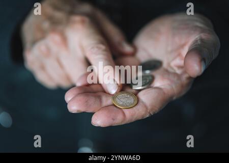 Defokussierter Blick auf ältere Frauen zählt Metallmünzen, faltige weibliche Hände aus der Nähe. Armutsbegriff, Pensionszahlungen, Rentner mit Geld. Armut Stockfoto