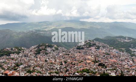 Ein Panoramablick auf Taxco de Alarcon zeigt die einzigartige Architektur der Stadt, eingebettet in sanfte Berge. Das Bild fängt einen bewölkten Tag ein Stockfoto