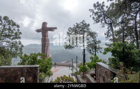 Eine majestätische Christusstatue mit ausgebreiteten Armen in Taxco de Alarcon, Mexiko, mit Blick auf die üppige Landschaft. Das umliegende Grün und die Bäume Stockfoto