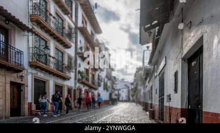 In Taxco de Alarcon, Mexiko, schlängeln sich kopfsteingepflasterte Straßen durch wunderschön erhaltene Kolonialgebäude, die mit bunten Blumen geschmückt sind. Menschen spazieren, e Stockfoto