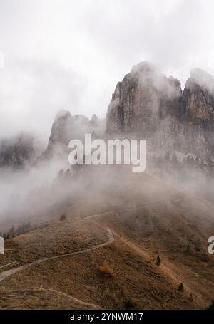 Ein Wanderweg, der durch Bergnebel in eine felsige Alpenlandschaft führt Stockfoto