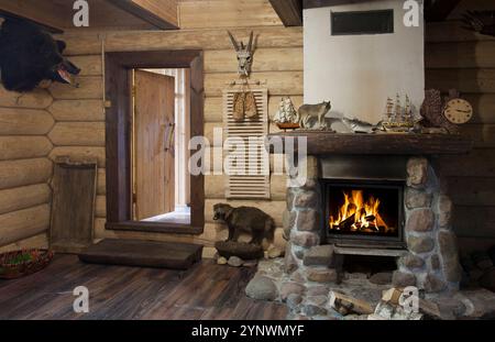 Das Innere des Jägerhauses mit brennendem Kamin und gefülltem Wildschweinkopf an der Wand Stockfoto