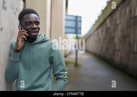 Teenager-Junge In Concrete Urban City Setting Mit Handy Sprechen Stockfoto