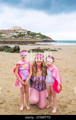 Die Teilnehmer treffen sich am Strand von Towan und bereiten sich auf die jährliche Veranstaltung „Superhero in the Cold“ vor, um Spenden für die britische Krebsforschung zu sammeln. Stockfoto