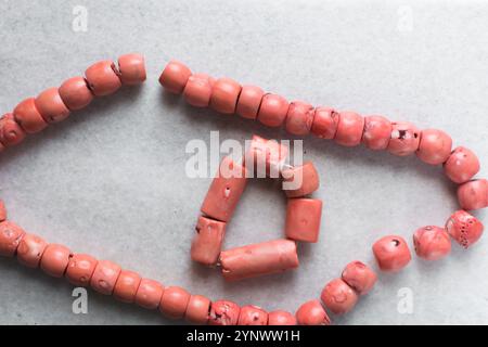 Blick von oben auf echte rosa Korallenperlen auf einem Marmortablett, Blick von oben auf große rosa Korallenperlen auf einem weißen Tisch Stockfoto