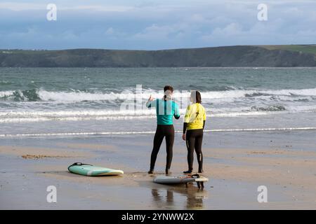 Ein Surflehrer der Escape Surfing School, der eine Surfstunde mit einem Anfänger am Towan Beach in Newquay Cornwall, Großbritannien, hält. Stockfoto