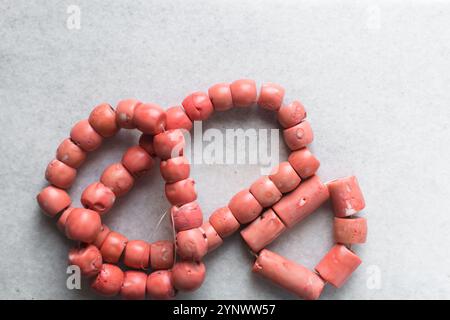 Blick von oben auf echte rosa Korallenperlen auf einem Marmortablett, Blick von oben auf große rosa Korallenperlen auf einem weißen Tisch Stockfoto