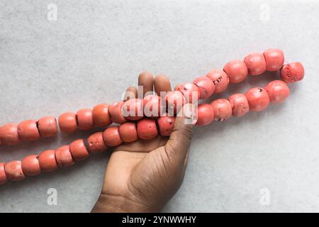 Blick von oben auf echte rosa Korallenperlen auf einem Marmortablett, Blick von oben auf große rosa Korallenperlen auf einem weißen Tisch Stockfoto