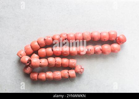 Blick von oben auf echte rosa Korallenperlen auf einem Marmortablett, Blick von oben auf große rosa Korallenperlen auf einem weißen Tisch Stockfoto