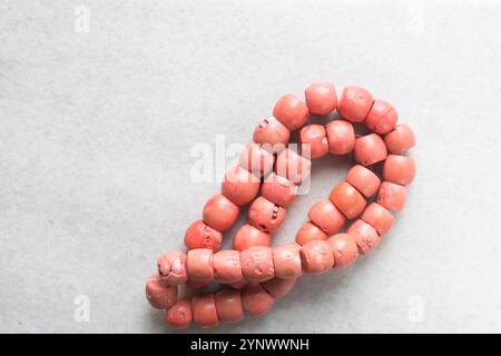 Blick von oben auf echte rosa Korallenperlen auf einem Marmortablett, Blick von oben auf große rosa Korallenperlen auf einem weißen Tisch Stockfoto