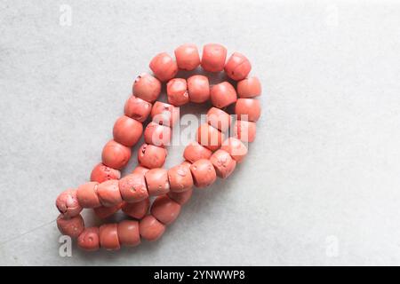 Blick von oben auf echte rosa Korallenperlen auf einem Marmortablett, Blick von oben auf große rosa Korallenperlen auf einem weißen Tisch Stockfoto