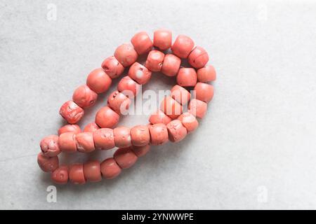 Blick von oben auf echte rosa Korallenperlen auf einem Marmortablett, Blick von oben auf große rosa Korallenperlen auf einem weißen Tisch Stockfoto