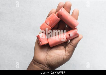 Blick von oben auf echte rosa Korallenperlen in braunen Händen, Blick von oben auf große rosa Korallenperlen Stockfoto