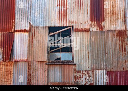 Kaputtes Fenster, verrosteter Schuppen, verfallene Gebäudewand, mit rostigem Wellblech, Hintergründe aus der Nähe Stockfoto