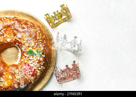 Blick von oben auf Roscon de reyes auf einem goldenen Teller mit Kronen der Weisen und Platz für Text auf einem schneebedeckten Hintergrund. Kings Day Concept spanisch drei Ki Stockfoto