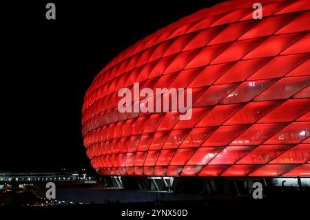 München, Deutschland, 26. November 2024: Fussball, Herren, Champions League, Saison 2024/2025, FC Bayern München - FC Paris Saint-Germain, Allianz Arena, 5.Spieltag hier die Aussenansicht der Allianz Arena, rot beleuchtet, Nacht, Dunkel, FC Bayern München, Heimspielstätte, Fussballstadion Stockfoto