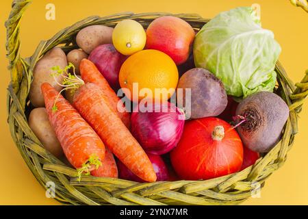 Gemüse und Obst in einem Korb auf gelbem Hintergrund Stockfoto