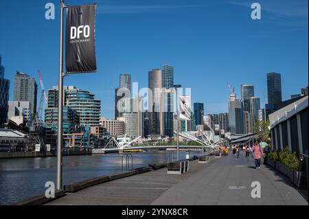 28.10.2024, Melbourne, Victoria, Australien - die Leute spazieren entlang der South Wharf Promenade am Yarra River mit der Skyline des Melbourne CBD in Southbank. Stockfoto