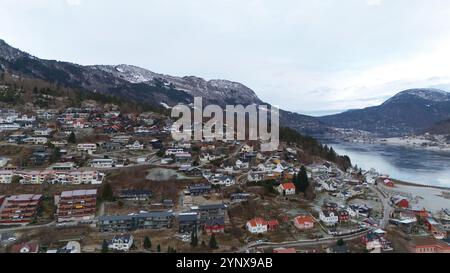Malerische Bergstadt in Norwegen mit Blick auf einen ruhigen Fjord und schneebedeckte Gipfel Stockfoto