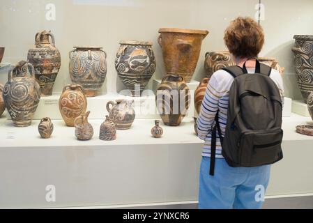 Blick auf eine reife weibliche Touristen, die eine Ausstellung dekorierter Schiffe aus der alten minoischen Zeit studiert, Heraklion Archäolologisches Museum, Kreta Stockfoto