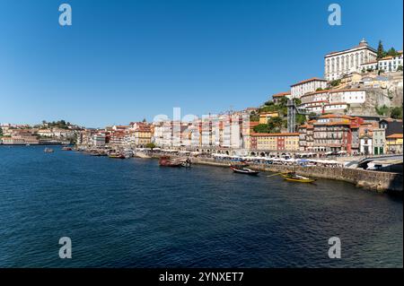 Porto, Portugal - 13. September 2024 : wunderschöne Flusslandschaft in Porto mit Booten und farbenfrohen Gebäuden unter klarem blauem Himmel Stockfoto