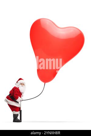 Der weihnachtsmann bläst einen herzförmigen Ballon, isoliert auf weißem Hintergrund Stockfoto